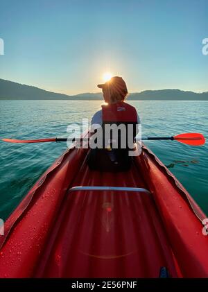 Donna in canoa su un lago di sera Foto Stock