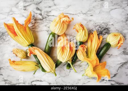 Courgette o zucca zucchina fresca con fiori su sfondo marmoreo. Immagine ripresa dalla vista superiore. Foto Stock