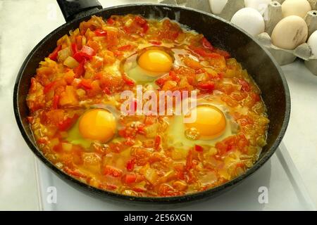 Cottura delle uova fritte shakshuka in salsa di verdure in padella. Cucina ebraica e arabica. Ricetta di Shakshuka. Primo piano. All'interno. Foto Stock