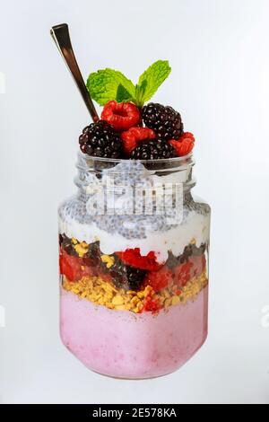 Budino di frutti di bosco con frutti di bosco freschi, muesli di muesli e semi di cia in vaso di vetro. Foto Stock