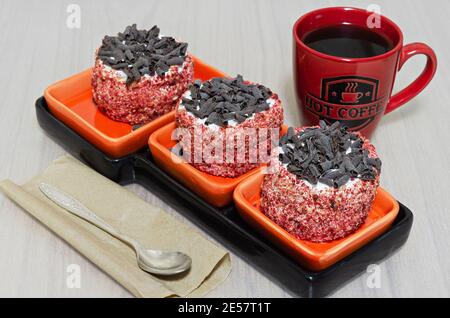 Torte con panna e cioccolato e una tazza di caffè caldo sul tavolo Foto Stock