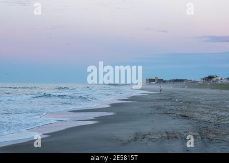 Una spiaggia quasi vuota in luce prima dell'alba. Foto Stock