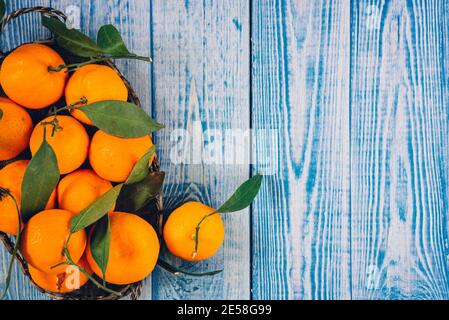 Frutta Mandarina matura sbucciata aperta e posto su vecchio rustico aspetto legno con gruppo di frutti di mandarino e foglie fuori fuoco sullo sfondo. Foto Stock
