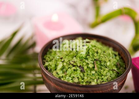 Centro benessere. Sale verde di spirulina a base di erbe in ciotola di ceramica, asciugamani termali, candela rosa profumata e bambù. Foto Stock