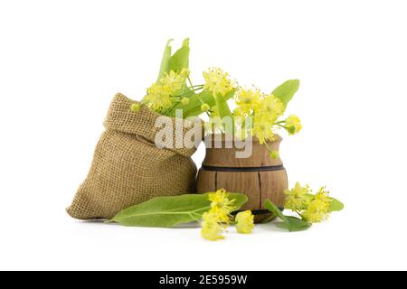 Piccolo vaso di legno e piccolo sacchetto hessiano di fiori e foglie di tiglio giallo appena raccolti, anche chiamato tilia e calce, per fare un tisane di guarigione o. Foto Stock