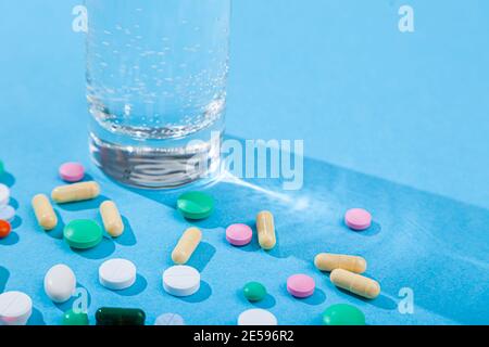 Compresse colorate sparse, vetro d'acqua, blister con pillole mediche, multivitamine Foto Stock