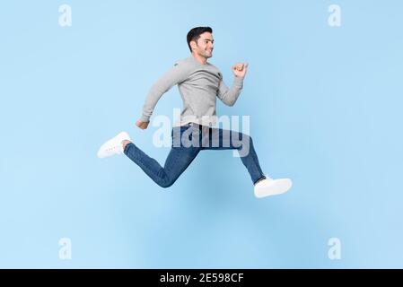 Sorridente bell'uomo che salta in uno studio isolato di colore azzurro sfondo Foto Stock