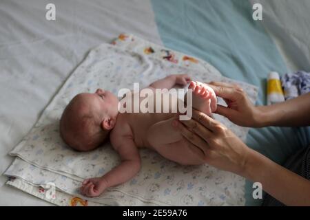 Bambino neonato che fa esercizi su un letto a casa Foto Stock