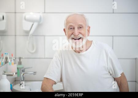 Uomo dai capelli grigi in camicia bianca ridendo vigorosamente Foto Stock