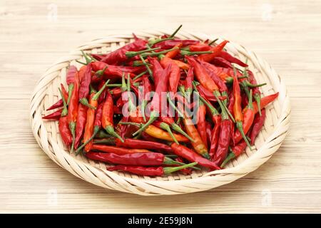 Piante secche di peperoncino rosso in cesto di bambù su legno tabella Foto Stock
