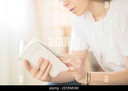 Mani piegate in preghiera su una Sacra Bibbia nel concetto di chiesa per fede, spiritualità e religione, donna che legge la santa bibbia al mattino. Foto Stock