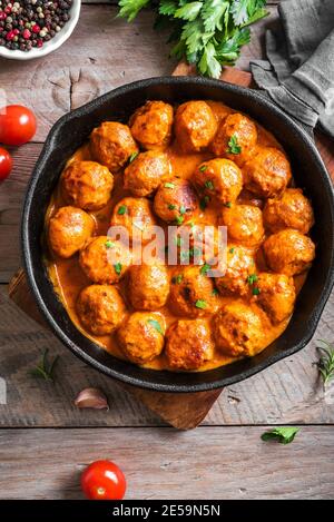 Polpette fatte in casa con salsa di pomodoro. Polpette di manzo in teglia di ghisa su sfondo di legno. Foto Stock