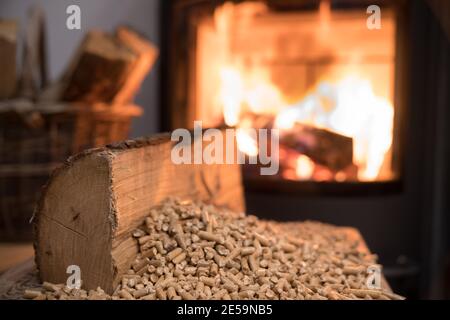 Stufa a legna con in primo piano pellet di legno - economico concetto di impianto di riscaldamento Foto Stock