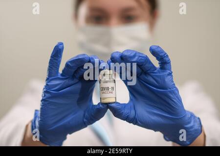 COVID-19. Concetto di coronavirus. Una fiala con un vaccino nella mano del medico o degli infermieri. Foto Stock