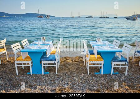 Carino tavolo e sedie e ombrellone in spiaggia al ristorante sul mare a bodrum, Turchia Foto Stock
