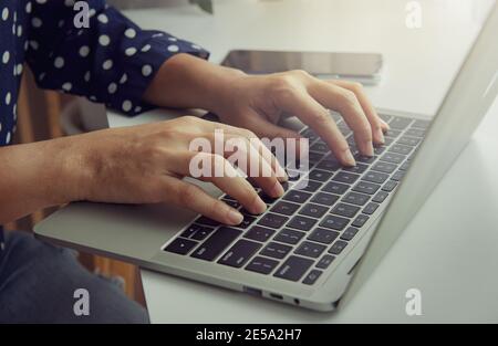 Mano della donna che usa una tastiera su un computer portatile. Concetto aziendale. Lavoro da casa. Foto Stock