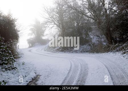 Country Lane con curve su strada e piste per pneumatici in un paesaggio invernale innevato Carmarthenshire Galles Regno Unito gennaio 2021 KATHY DEWITT Foto Stock