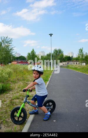 POZNAN, POLONIA - 09 luglio 2017: Ragazzo con casco di sicurezza seduto su una piccola bici da bilanciamento su un sentiero Foto Stock