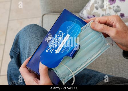Primo piano di uomo persona che prende protezione tenendo maschera di tenuta fuori da una scatola Foto Stock