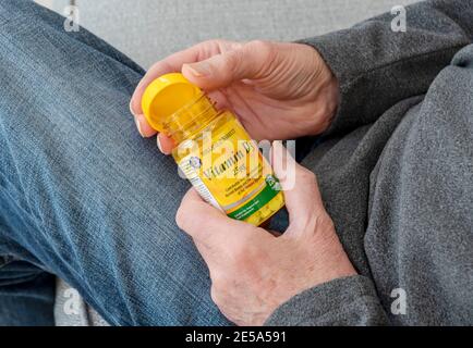 Primo piano dell'uomo che tiene il flacone di plastica di Vitamin D compresse supplemento Foto Stock