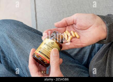 Primo piano dell'uomo persona che tiene una bottiglia di integratori di vitamina B compresse complesse Foto Stock