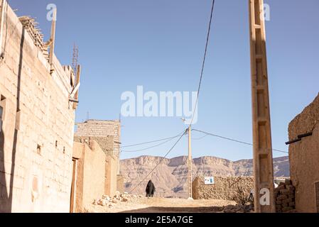 Donna musulmana che cammina per strada con edifici in rovina Marocco Foto Stock
