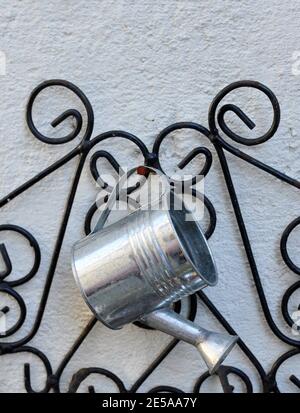 Piccolo irrigatore in metallo appeso, su uno sfondo bianco, primo piano, vista frontale Foto Stock