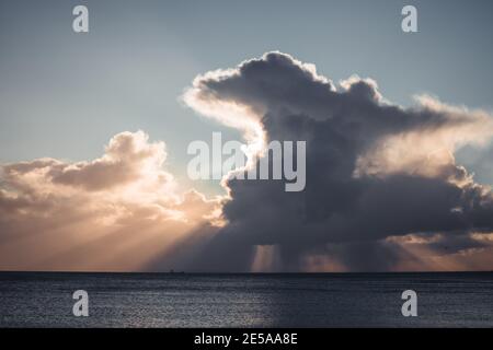 Grande nuvola di Cumulonimbus e raggi di sole all'orizzonte sopra Nave di trasporto al largo della costa di Penzance Foto Stock