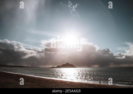 La silhouette del Monte St Michaels, il sole di Cornwall Beach si riflette sulle acque tranquille dell'oceano calmo Foto Stock