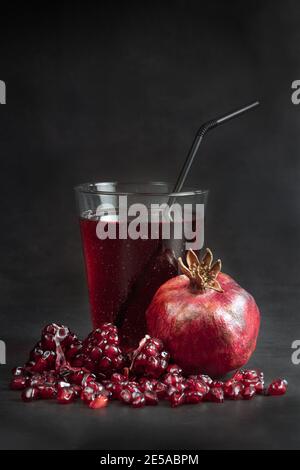 Succo di melograno e frutta fresca di grenadina sul tavolo su fondo nero. Foto Stock
