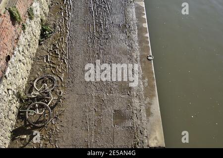 Maidstone, Kent, Regno Unito. Impronte, tracce di pneumatici e una vecchia bicicletta in fango spesso lasciata su un sentiero basso lungo il fiume dopo l'alluvione del fiume Medway, Foto Stock