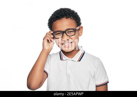 Bambino afroamericano sorridente con occhiali eleganti, isolato su sfondo bianco. Correzione della visione per i bambini Foto Stock