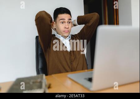 Ha sorpreso il giovane che guarda il suo laptop nel Foto Stock