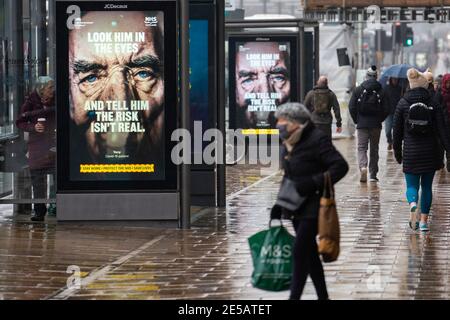 Edimburgo, Scozia, Regno Unito. 27 gennaio 2021. I membri del pubblico camminano oggi oltre il nuovo governo Covid-19 manifesti di avvertimento di salute su Princes Street a Edimburgo. Iain Masterton/Alamy Live News Foto Stock