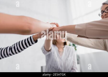 gruppo di donne multietniche che tengono le mani insieme durante il seminario Foto Stock