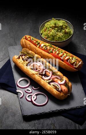 Gourmet panino hot dog sporco con varie guarnitura su sfondo di pietra nera. Opzione sana di fast food. Foto Stock