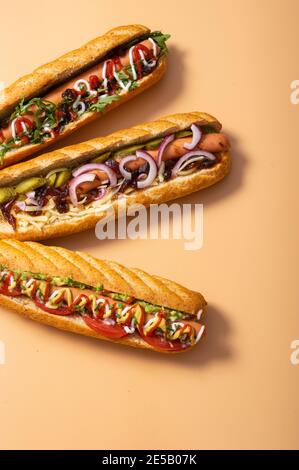 Gourmet panino hot dog sporco con varie guarnitura su sfondo giallo. Opzione sana di fast food. Foto Stock