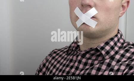 Un uomo a bocca chiusa con nastro a condotto, un uomo con nastro adesivo sulle labbra, un uomo a bocca chiusa. Foto Stock