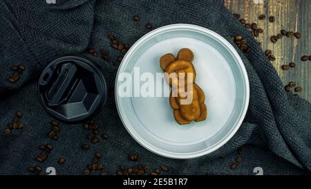 Prodotti da forno a base di orso, un bicchiere di caffè con dessert, una fragrante bevanda mattutina con biscotti, cereali fritti sono sparsi sul tavolo. Vista dall'alto. Foto Stock