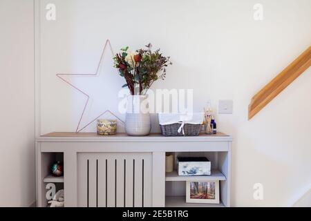 Una copertura radiatore corridoio che ha una stella, candela e un vaso di fiori su di esso ripiano più spray antibatterico Foto Stock