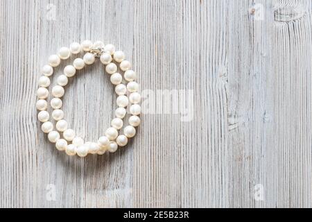 collana piegata in madreperla bianca naturale su sfondo grigio di legno con copyspace Foto Stock