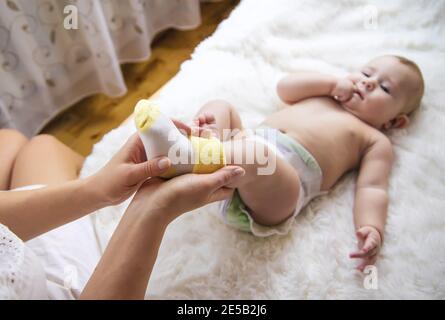 La madre mette i calzini sul bambino piccolo. Messa a fuoco selettiva. Persone. Foto Stock