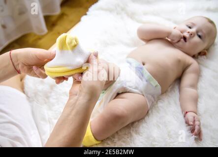 La madre mette i calzini sul bambino piccolo. Messa a fuoco selettiva. Persone. Foto Stock