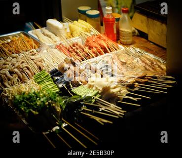 Vari spiedini di carne e verdure al mercato di strada in Cina. Notte Foto Stock
