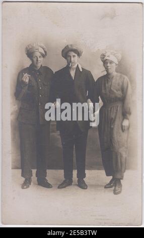 Tre lavoratori Hull munizioni in posa per la fotocamera. Due delle donne indossano abiti da uomo (una in uniforme da soldato) e la terza indossa un abito da lavoro (con pantaloni), tutte hanno sigarette silluminate. I distintivi triangolari dei lavoratori delle munizioni possono essere visti su due dei cappelli Foto Stock