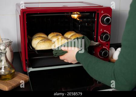 la donna toglie dal forno deliziose cabine di lievito fatte in casa. Foto Stock