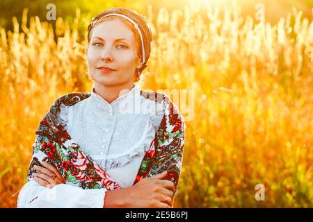 Giovane bella donna slovacca in costume tradizionale in estate Daisy prato durante il tramonto Foto Stock