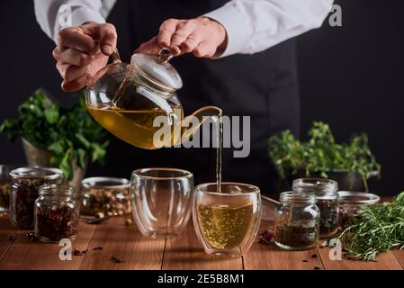 Barista che versa tè alle erbe fresco in tazze per due persone Foto Stock