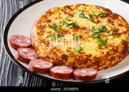 Deliziosi frittelle fritte con purè di patate e pancetta e crauti serviti con salsicce da vicino in un piatto sul tavolo. Orizzontale Foto Stock
