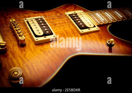 Primo piano di una chitarra elettrica d'epoca con finitura sunburst su a. sfondo nero Foto Stock